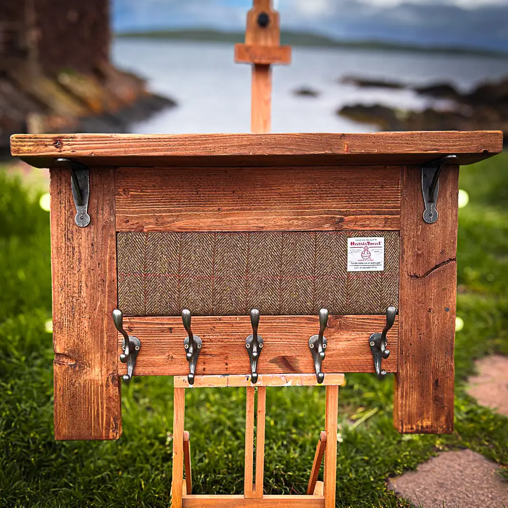 A hand crafted wooden coatrack with a harris tweed inlay against the Scottish Coastline.