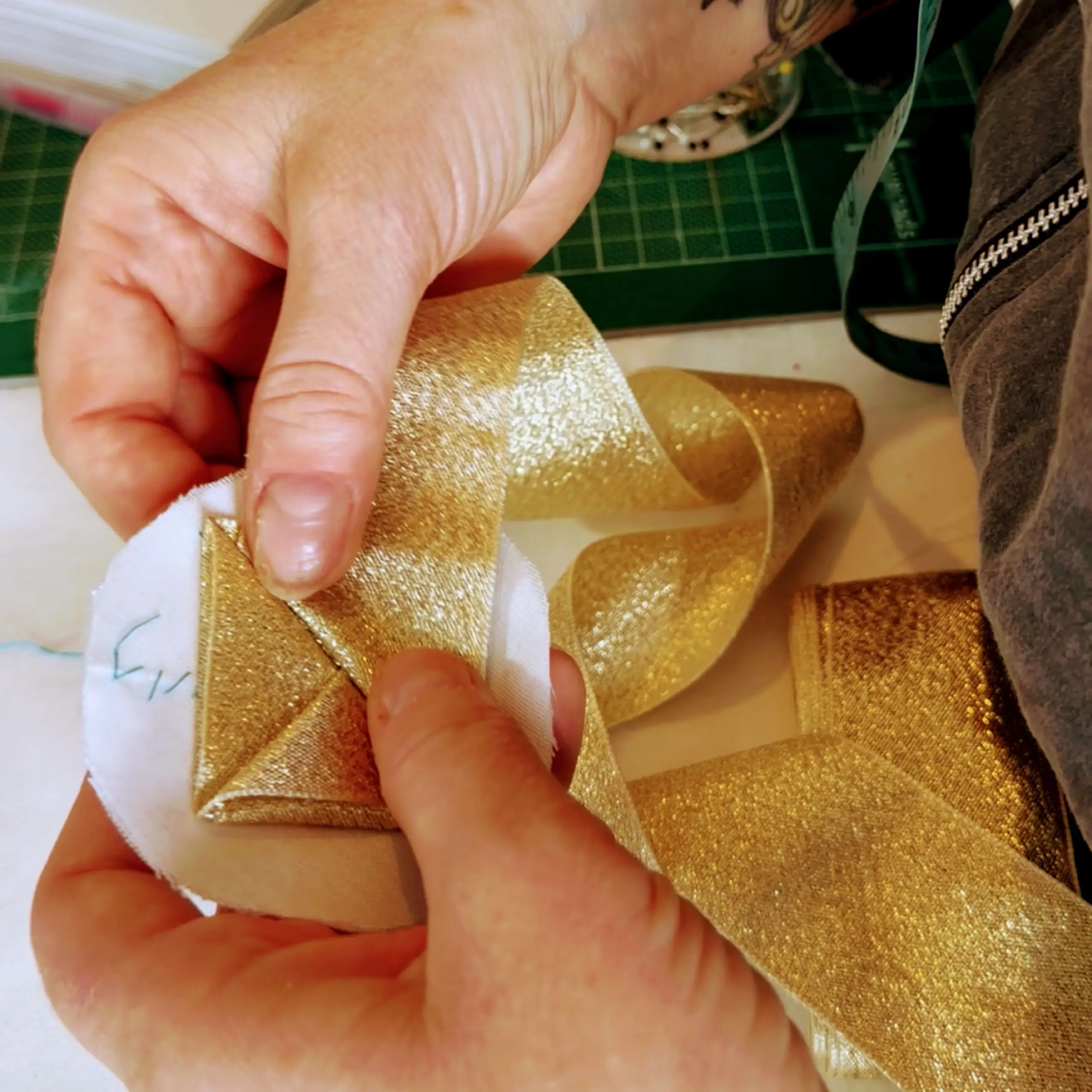 A pair of hands working with a golden ribbon.