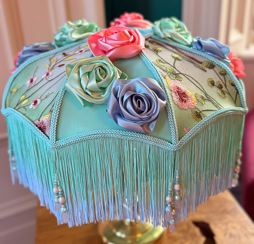 A highly decorative green floral lampshade on a brass base.