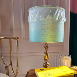 A blue silk drum lampshade sitting on a table.