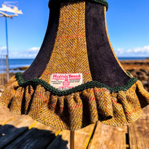 A green tweed and black velvet lampshade with a frill.