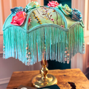 A highly decorative green floral lampshade on a brass base.