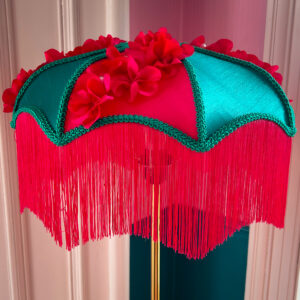 A green and pink silk lampshade with a deep pink fringe.